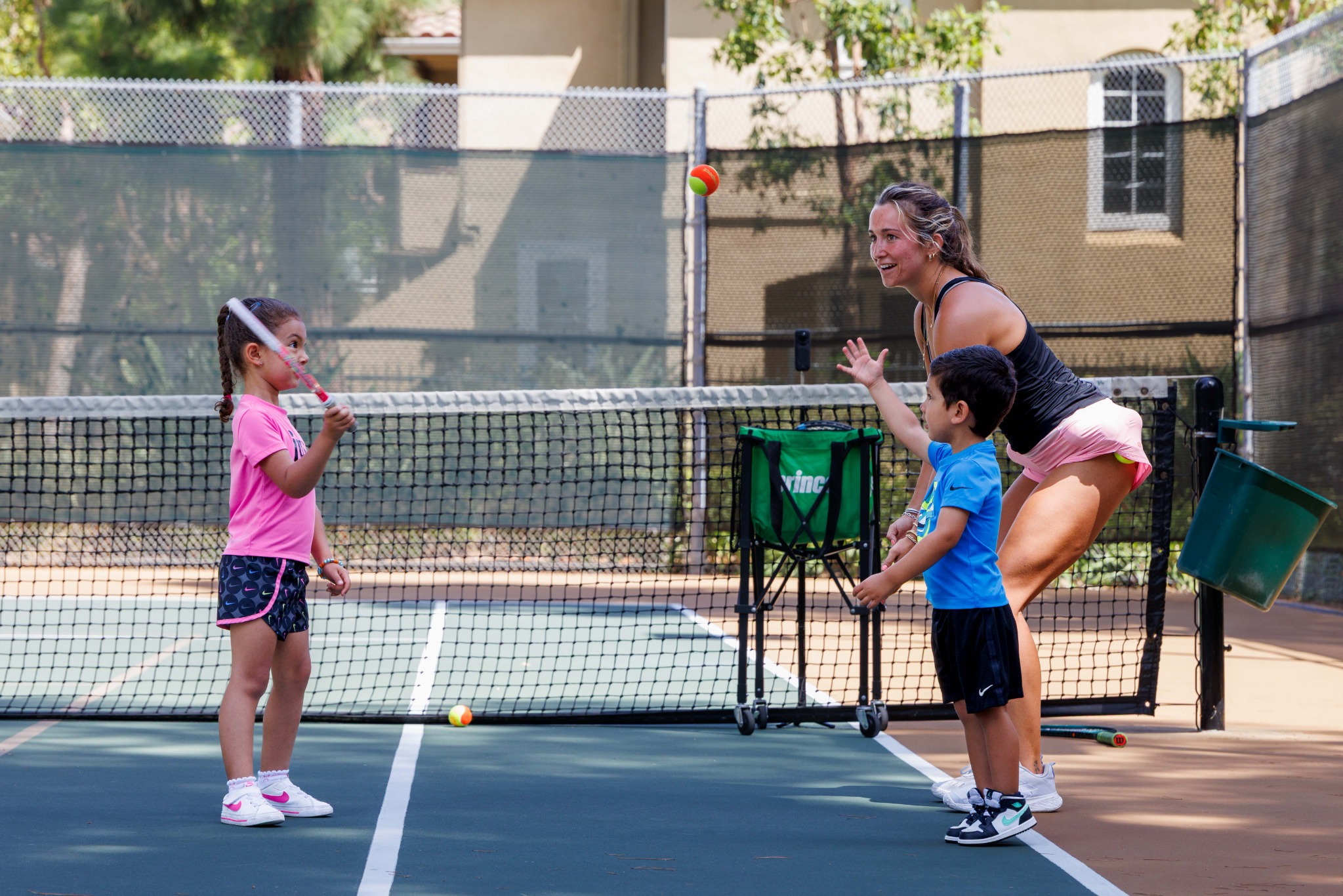 DB Tennis coach and children rallying on court