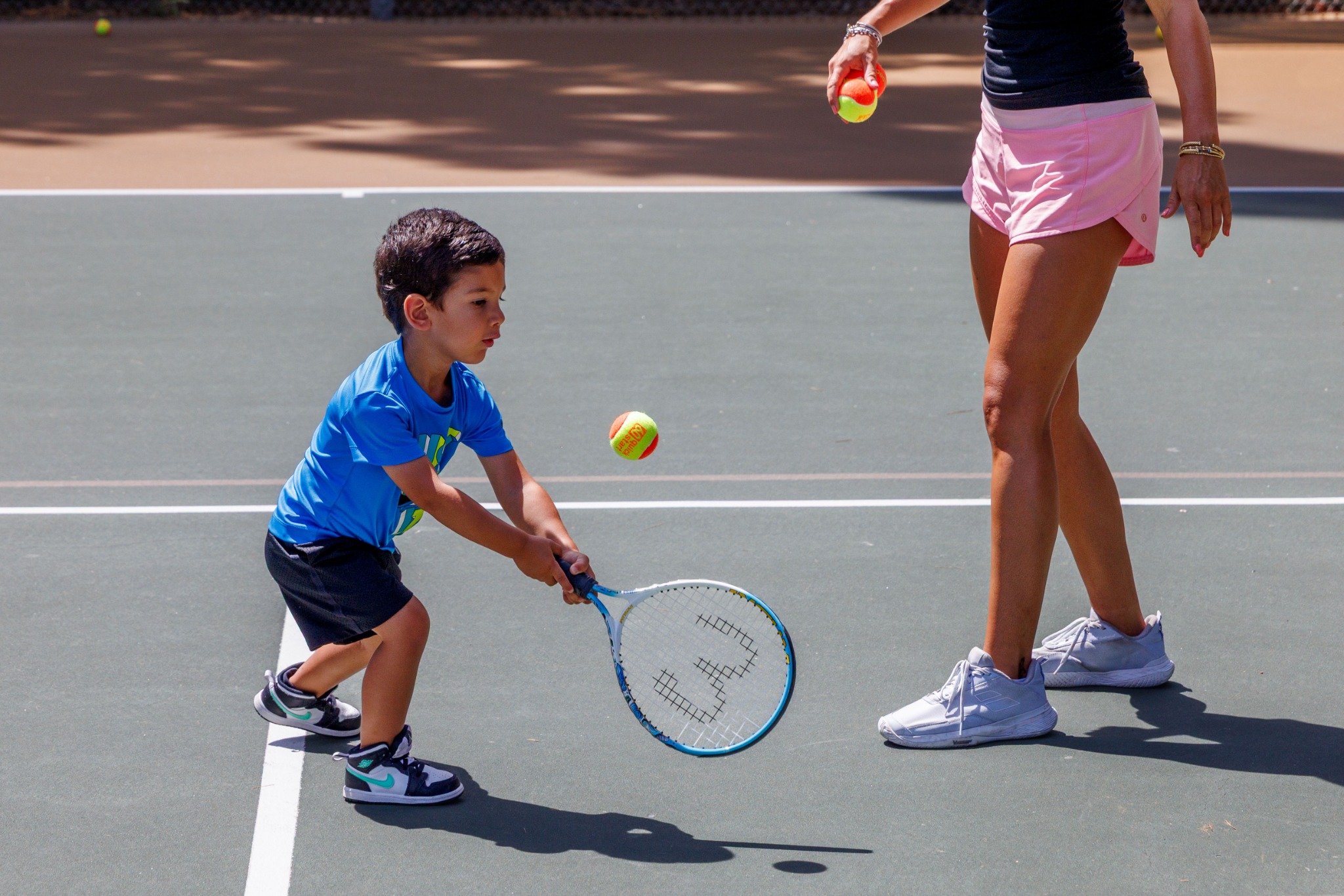 Young tennis player practicing a low ball