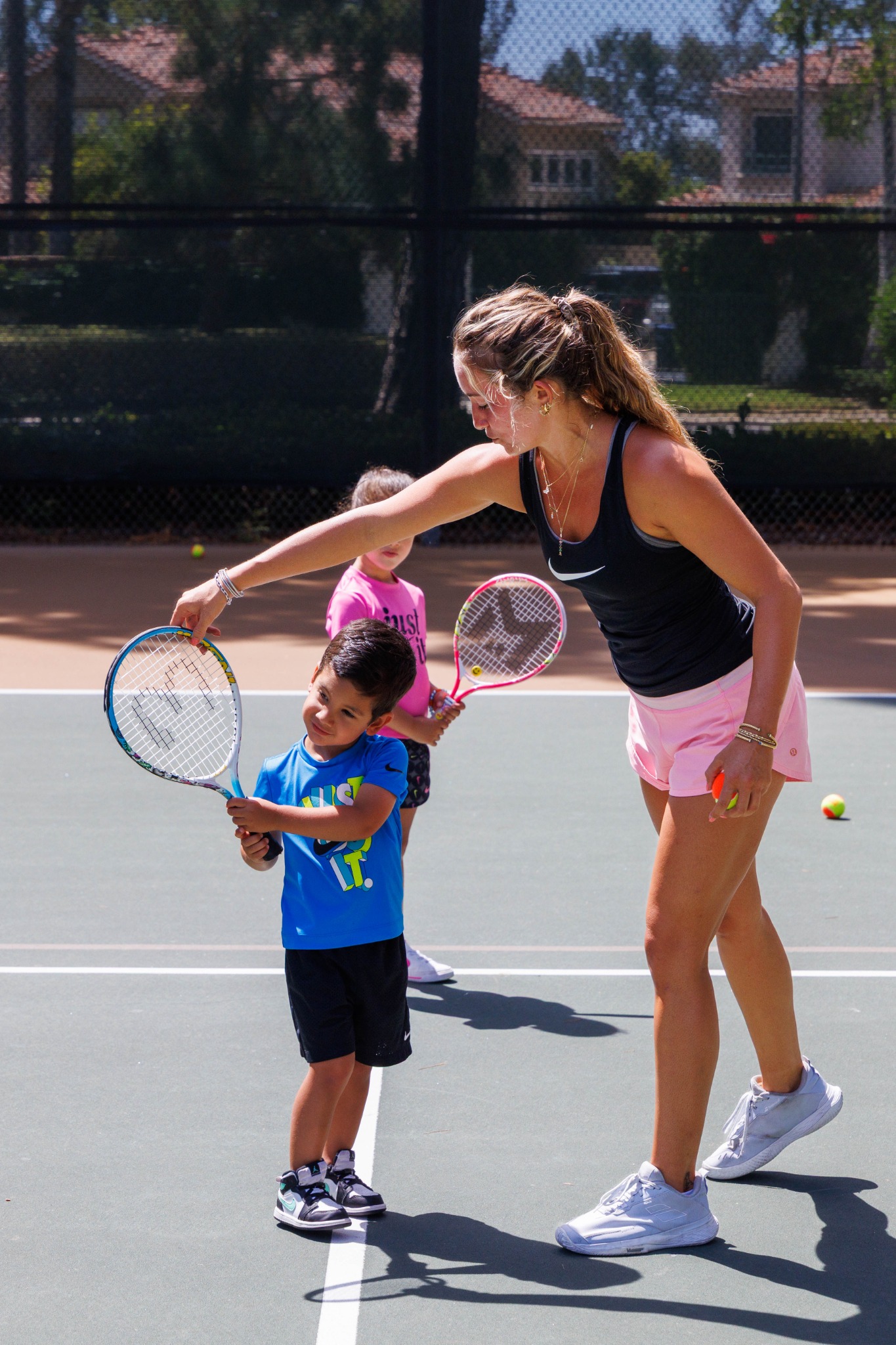 DB Tennis coach helping a young player with technique